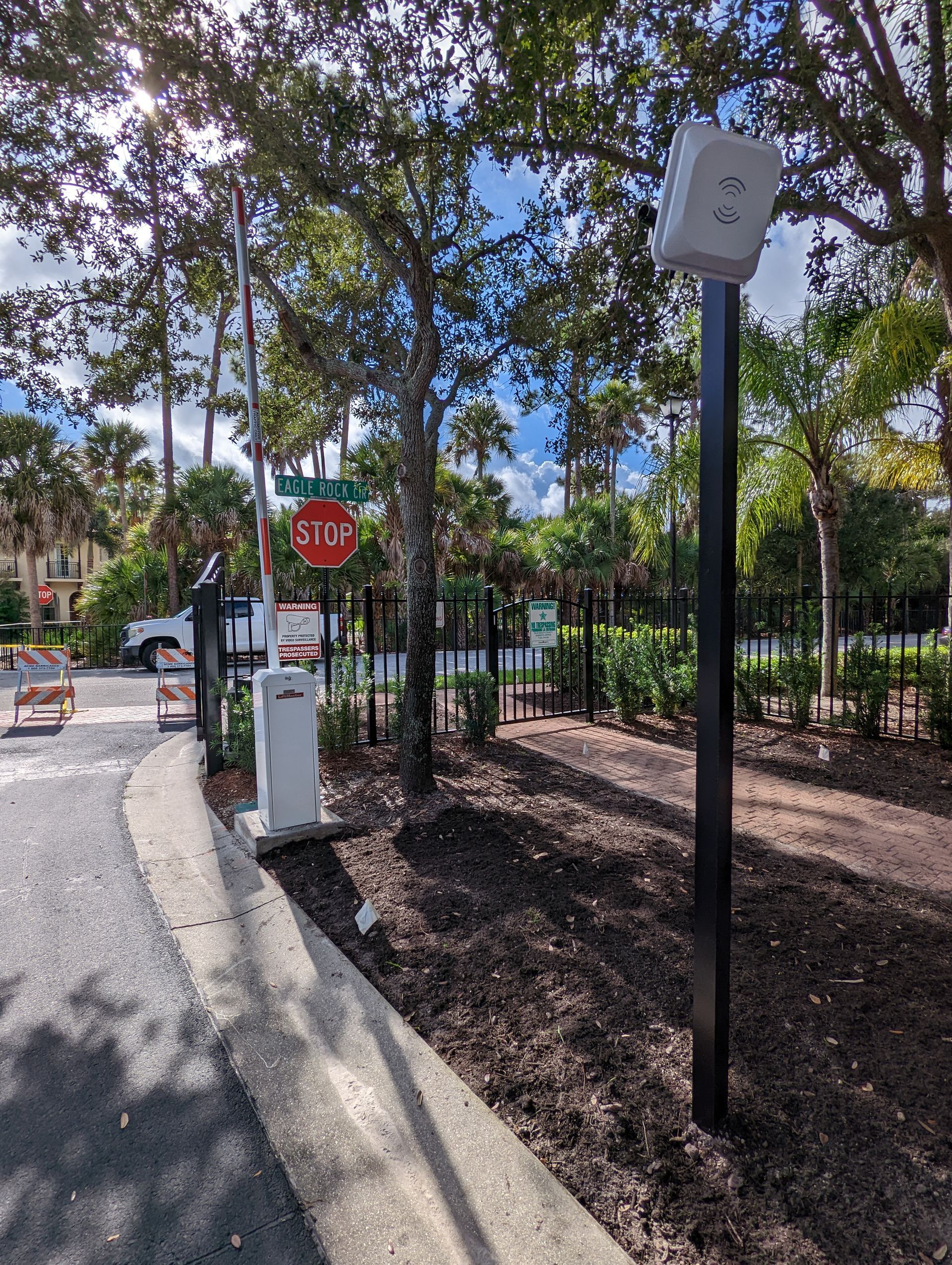 Park path with stop sign, lamp post, fence, and trees in a sunny outdoor area