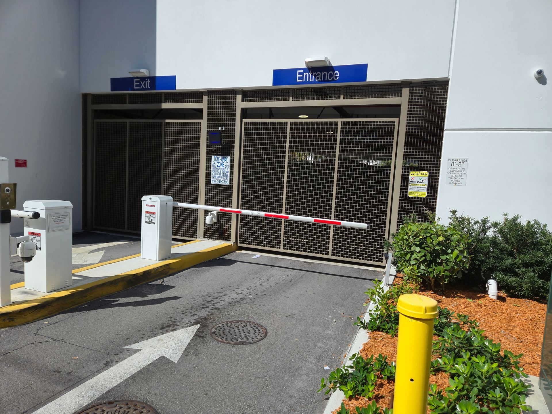 Garage entrance blocked by a red-and-white barrier gate, with parking lane and arrow markings nearby.