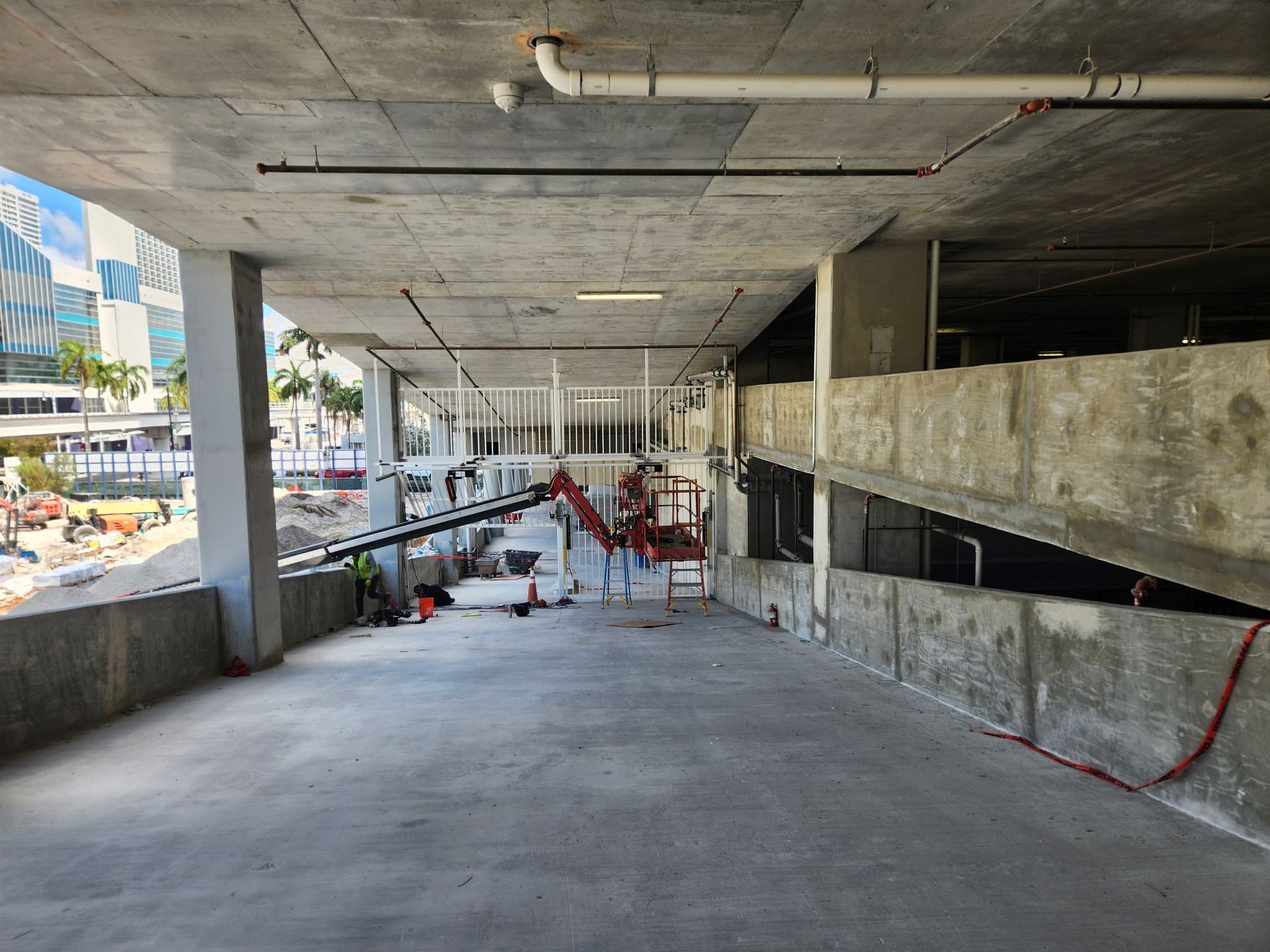 Concrete ramp under construction with red barriers and exposed beams in a parking structure