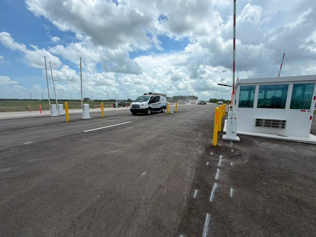 Car entering a toll plaza lane beside a white booth under a cloudy sky