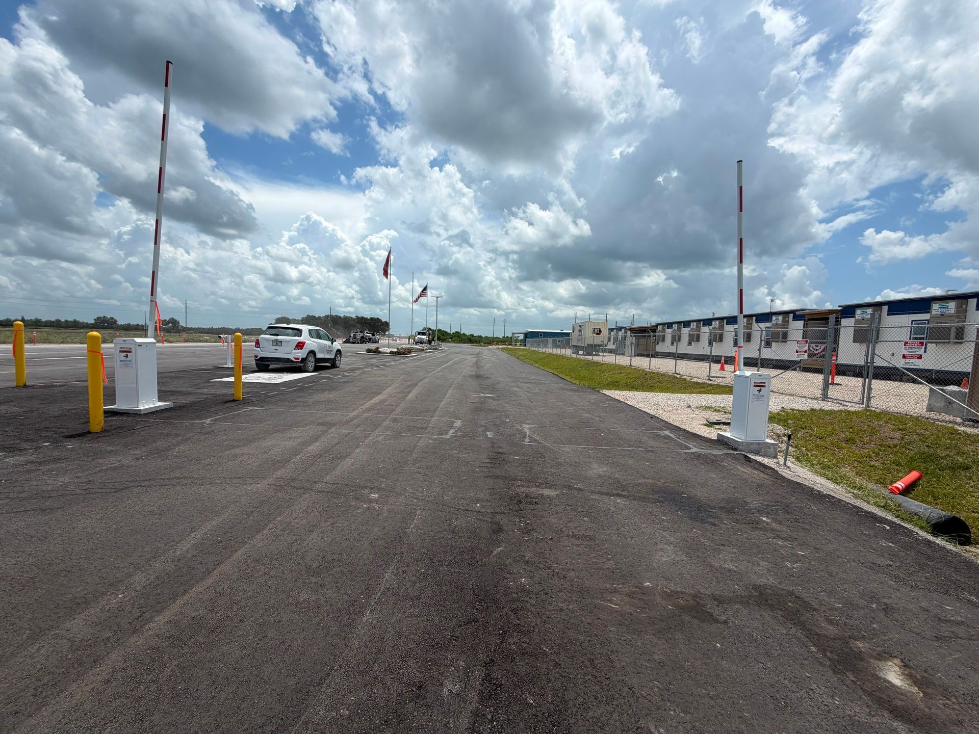 Construction road under cloudy sky with parked white trucks and row houses on the right