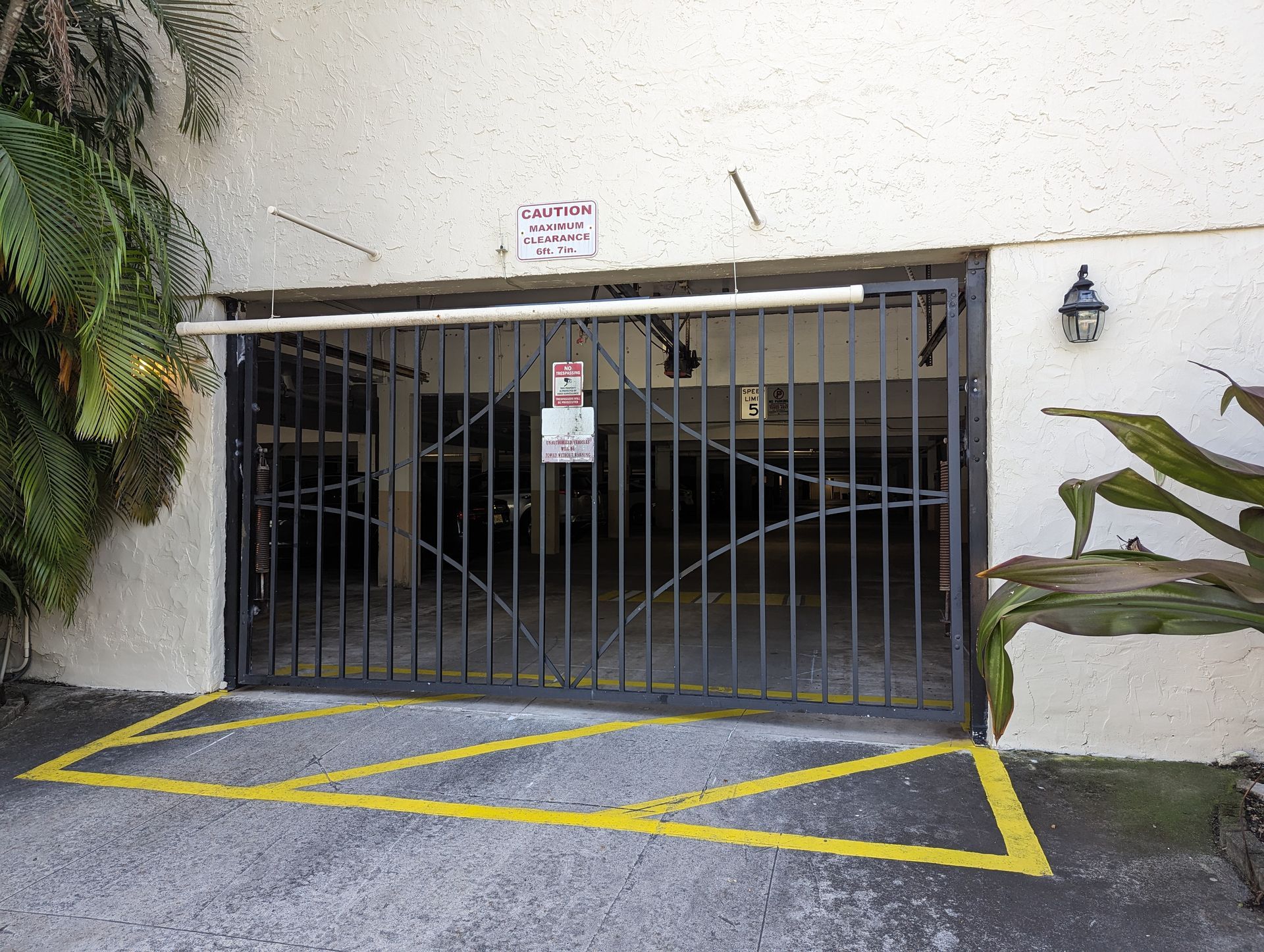 Gated parking garage entrance with yellow no-parking markings and a small sign above the gate