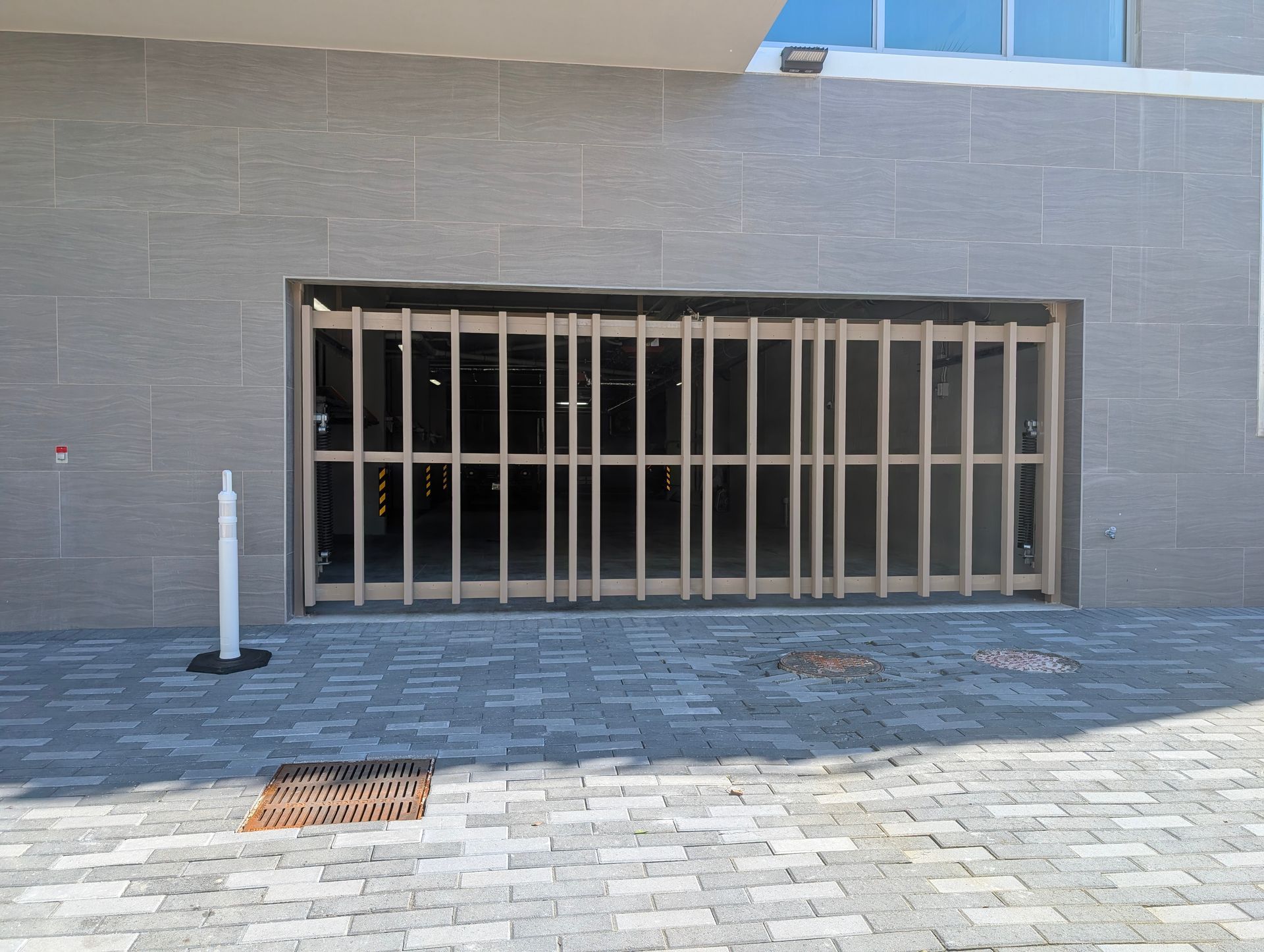 Exterior wall with a large barred opening and paved walkway in front