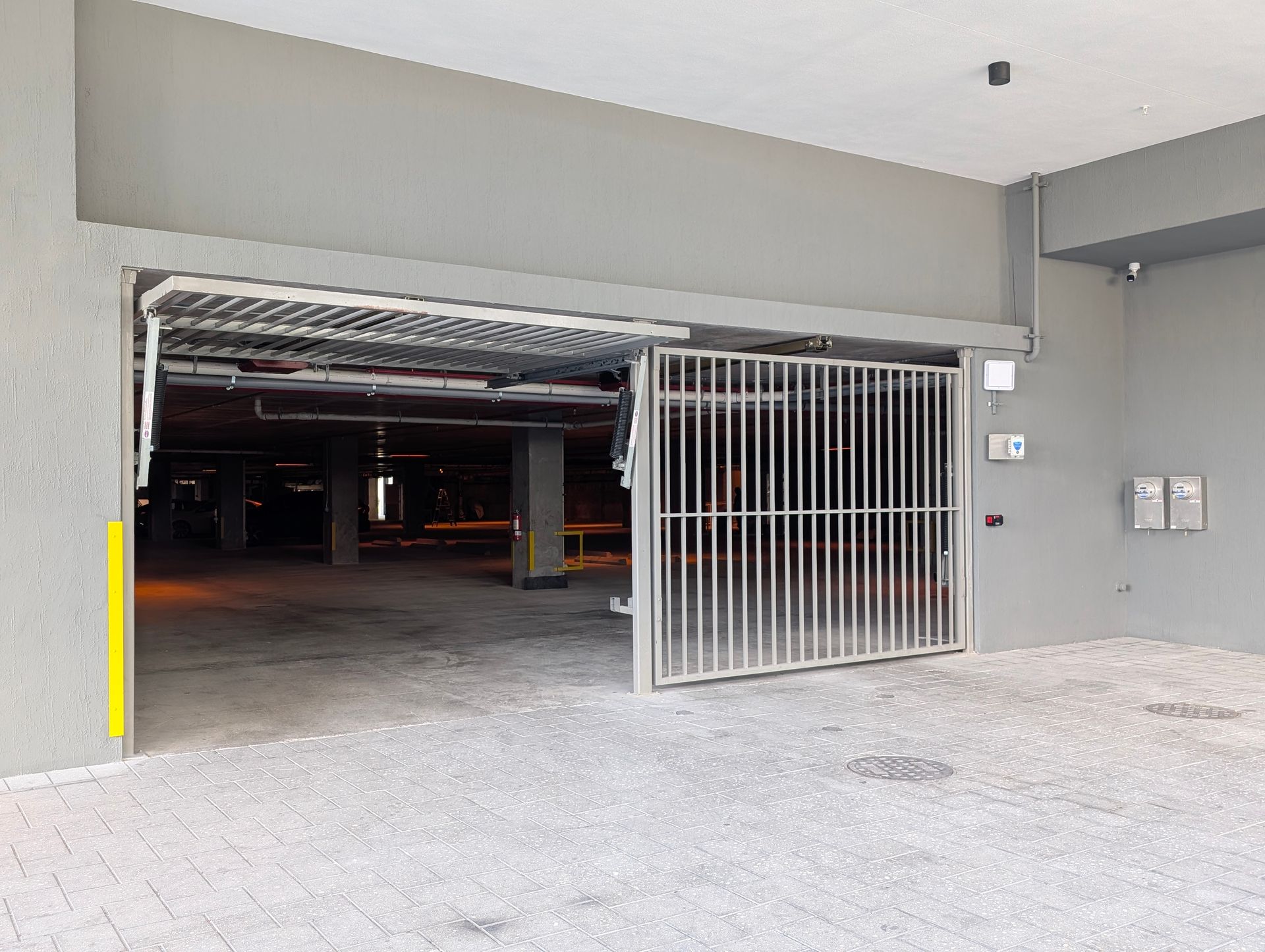Open parking garage entrance with a metal gate and concrete floor