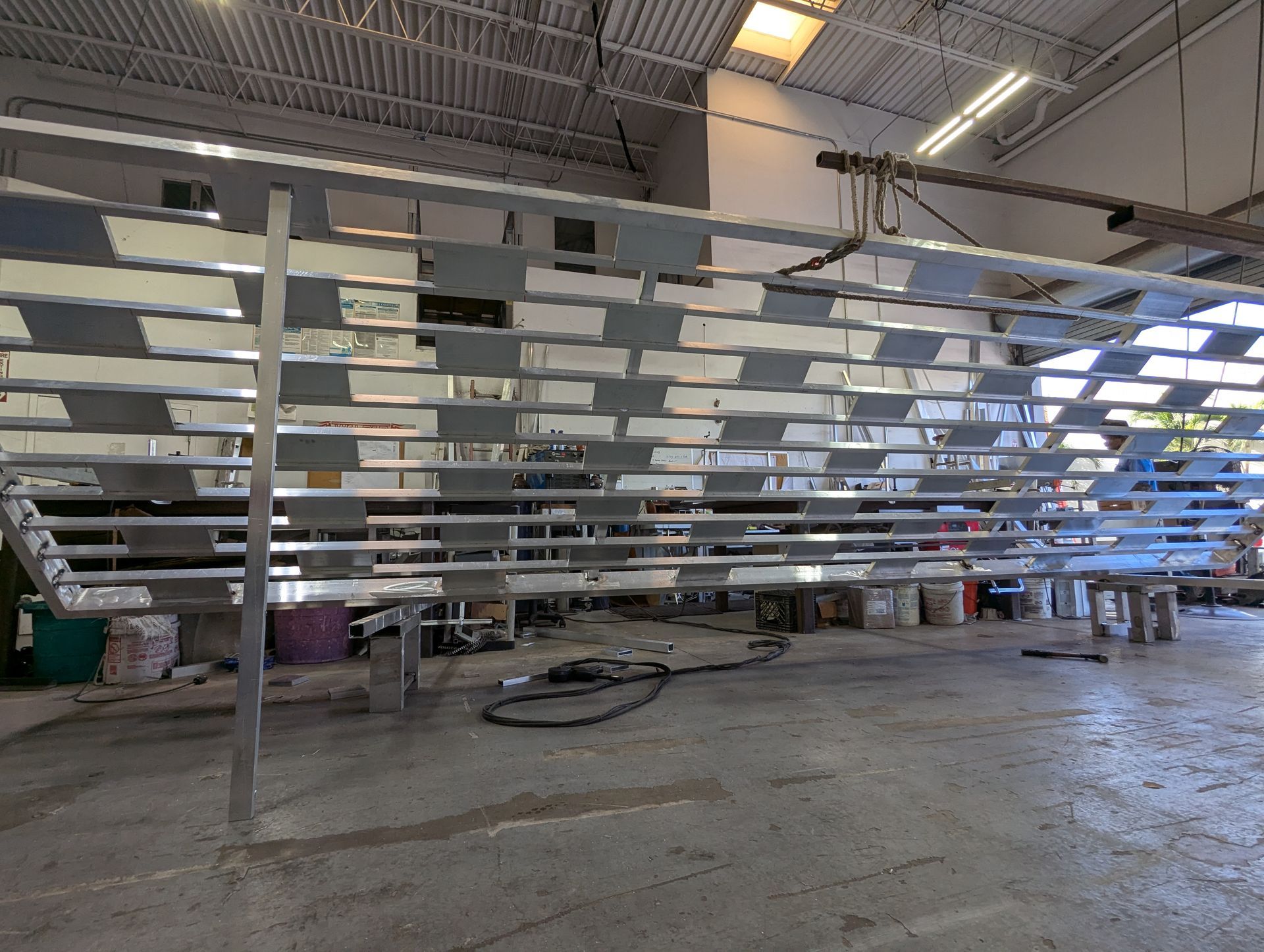 Large industrial workshop with a long metal rack structure under construction inside a warehouse.