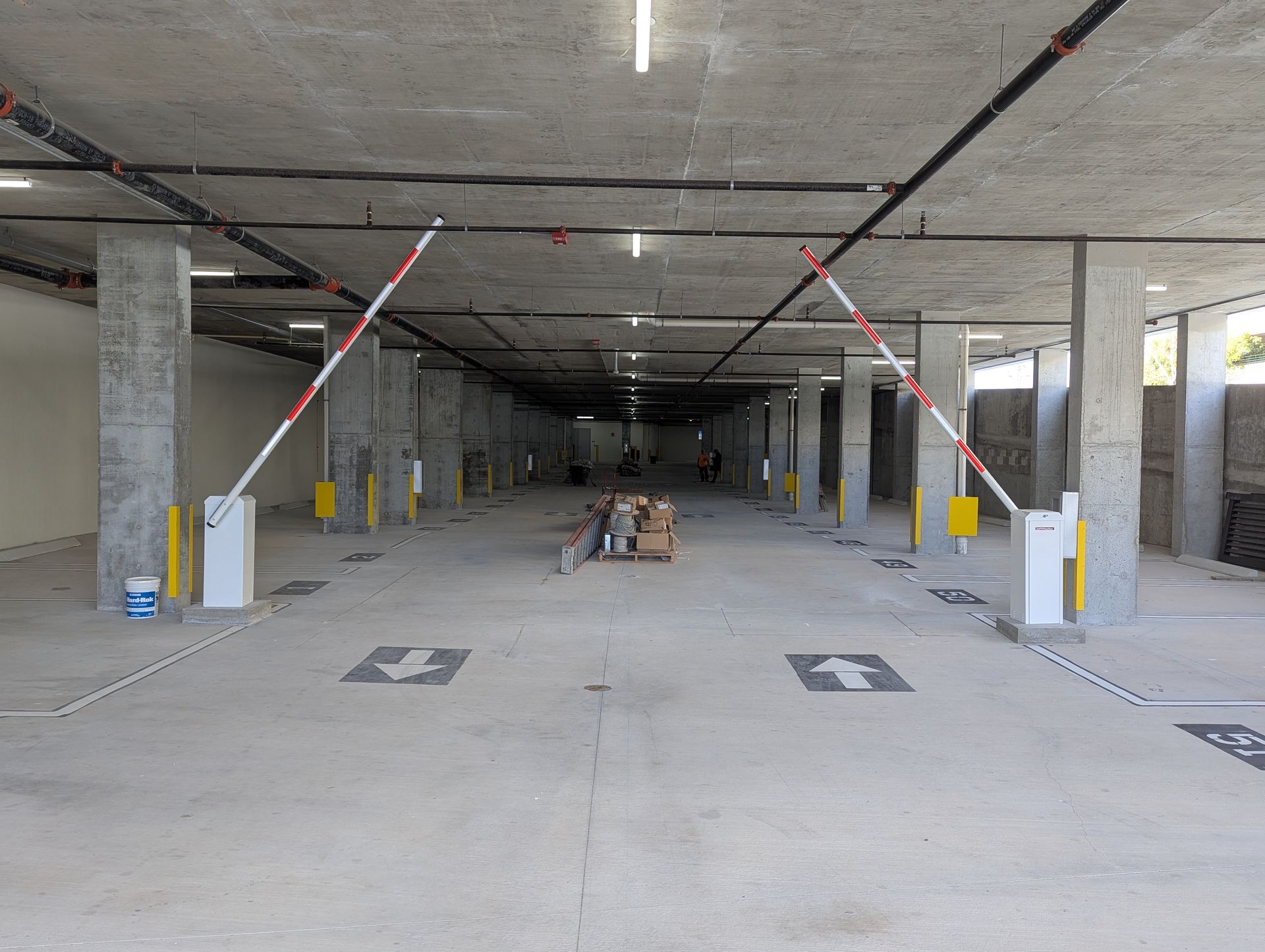 Empty parking garage entrance with raised barrier arms and directional arrows on the floor