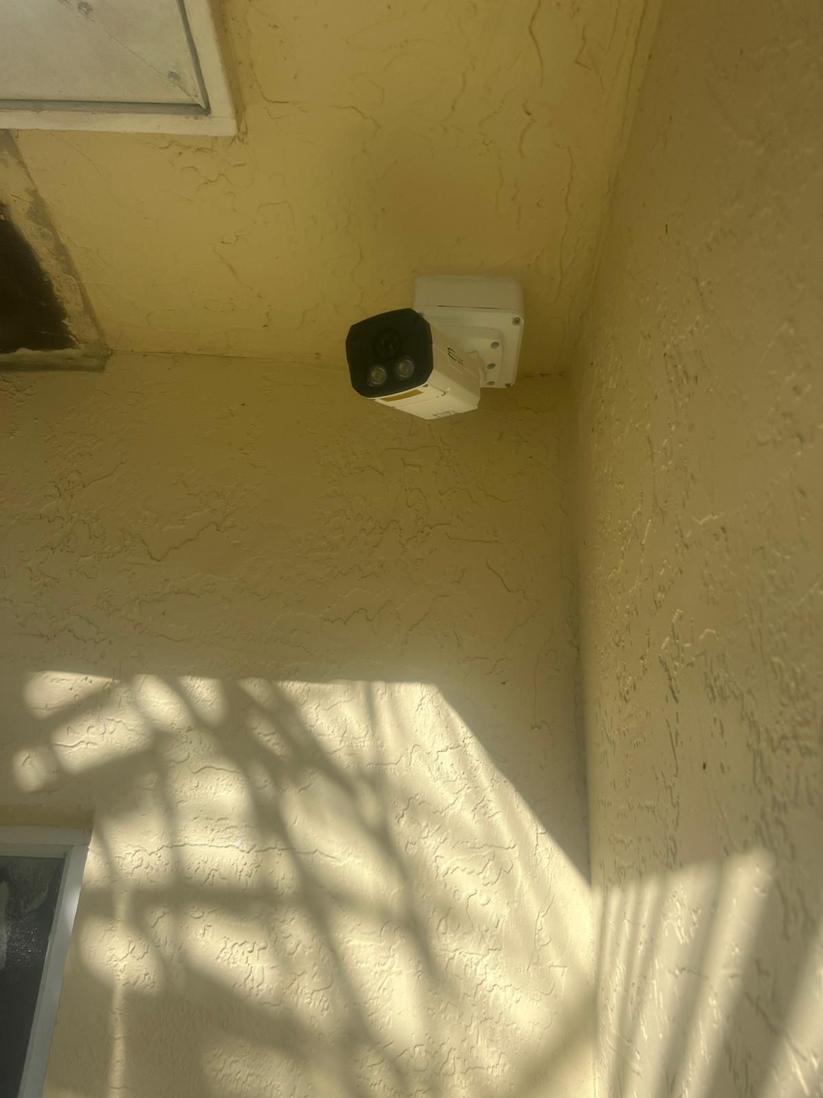 Security camera mounted on a beige exterior wall near the ceiling