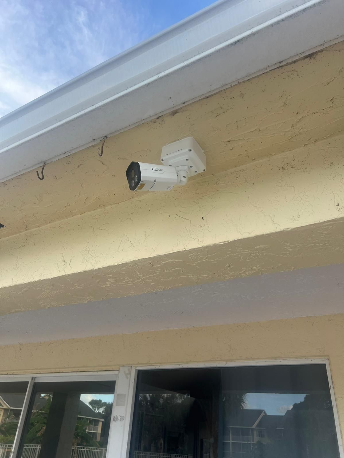 Security camera mounted under a house eave above a window.