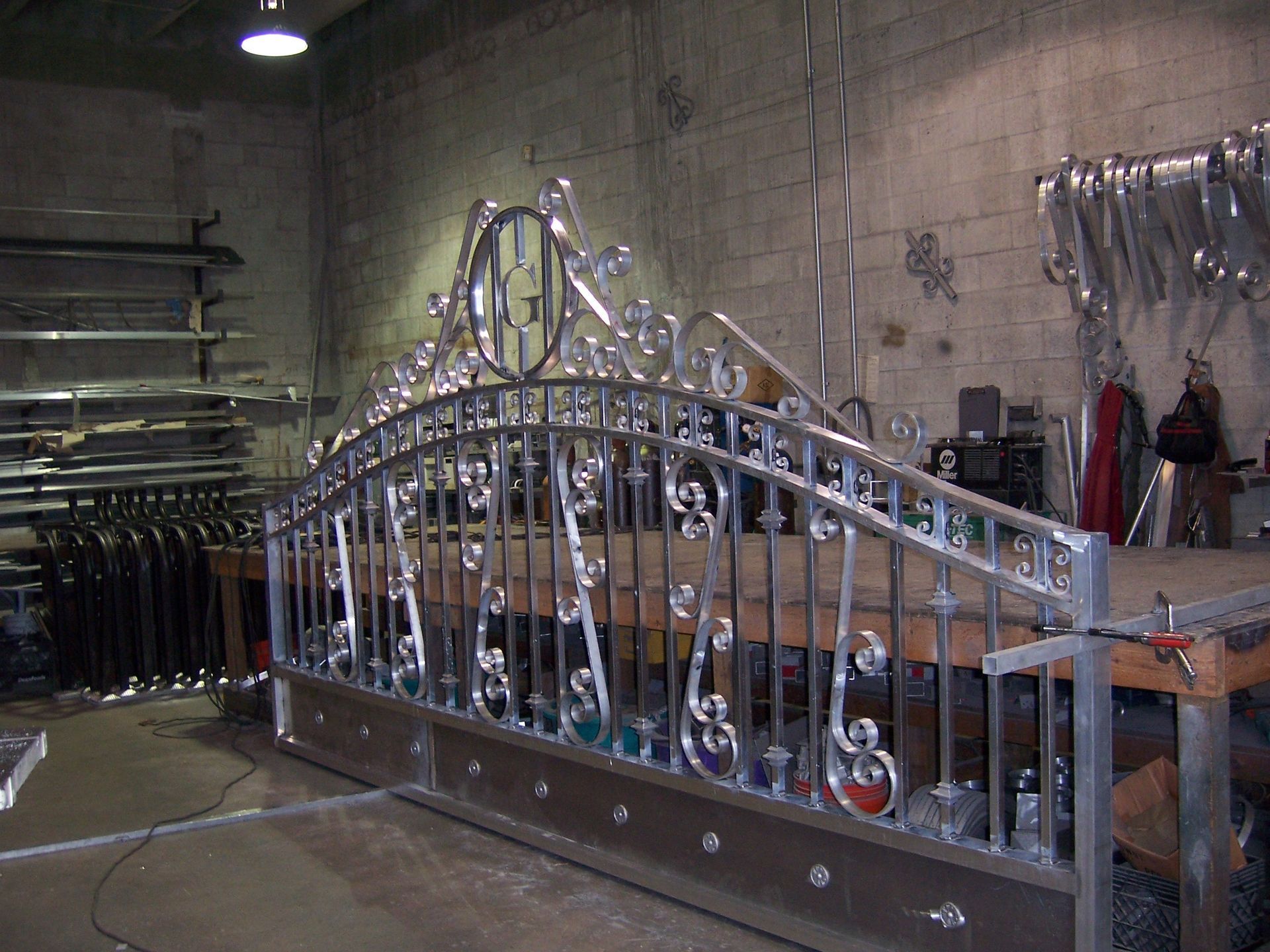 Metal bridge sculpture in a workshop, with ornate silver railings and unfinished wooden supports