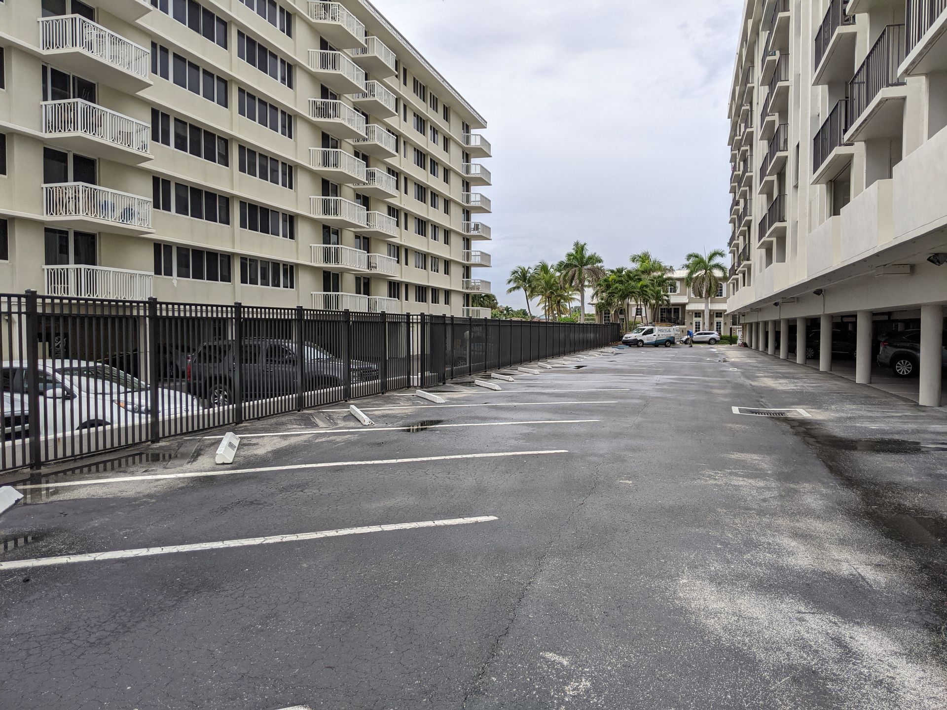Empty parking lot between apartment buildings with palm trees in the distance