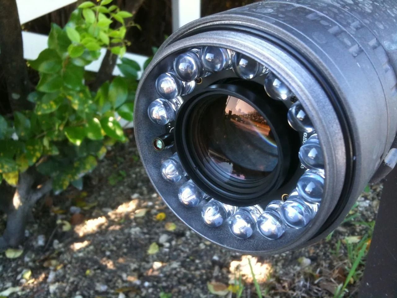 Close-up of a black camera or sensor lens with a ring of LED lights outdoors