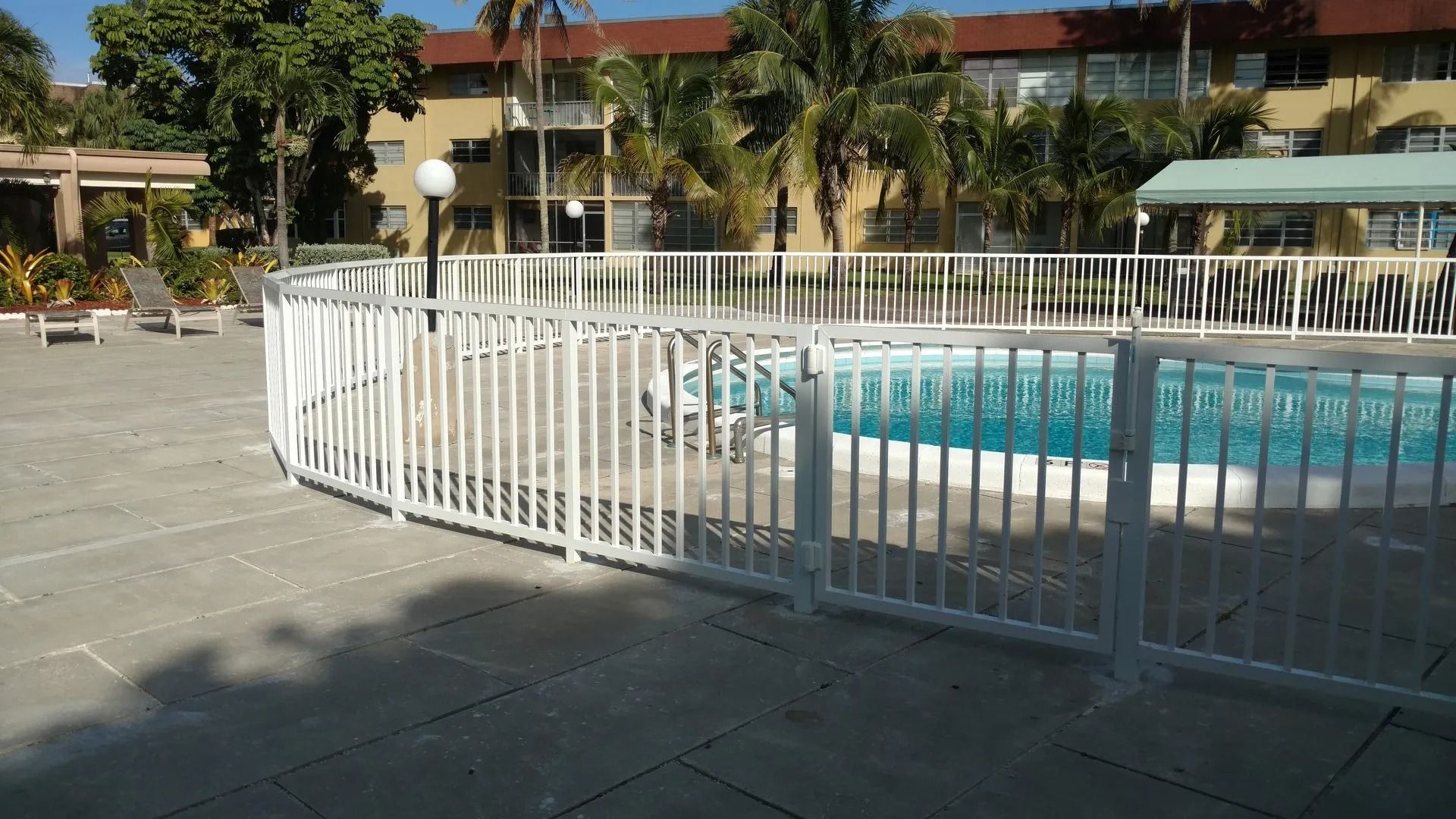 Courtyard pool with white railing and stone patio in front of a building