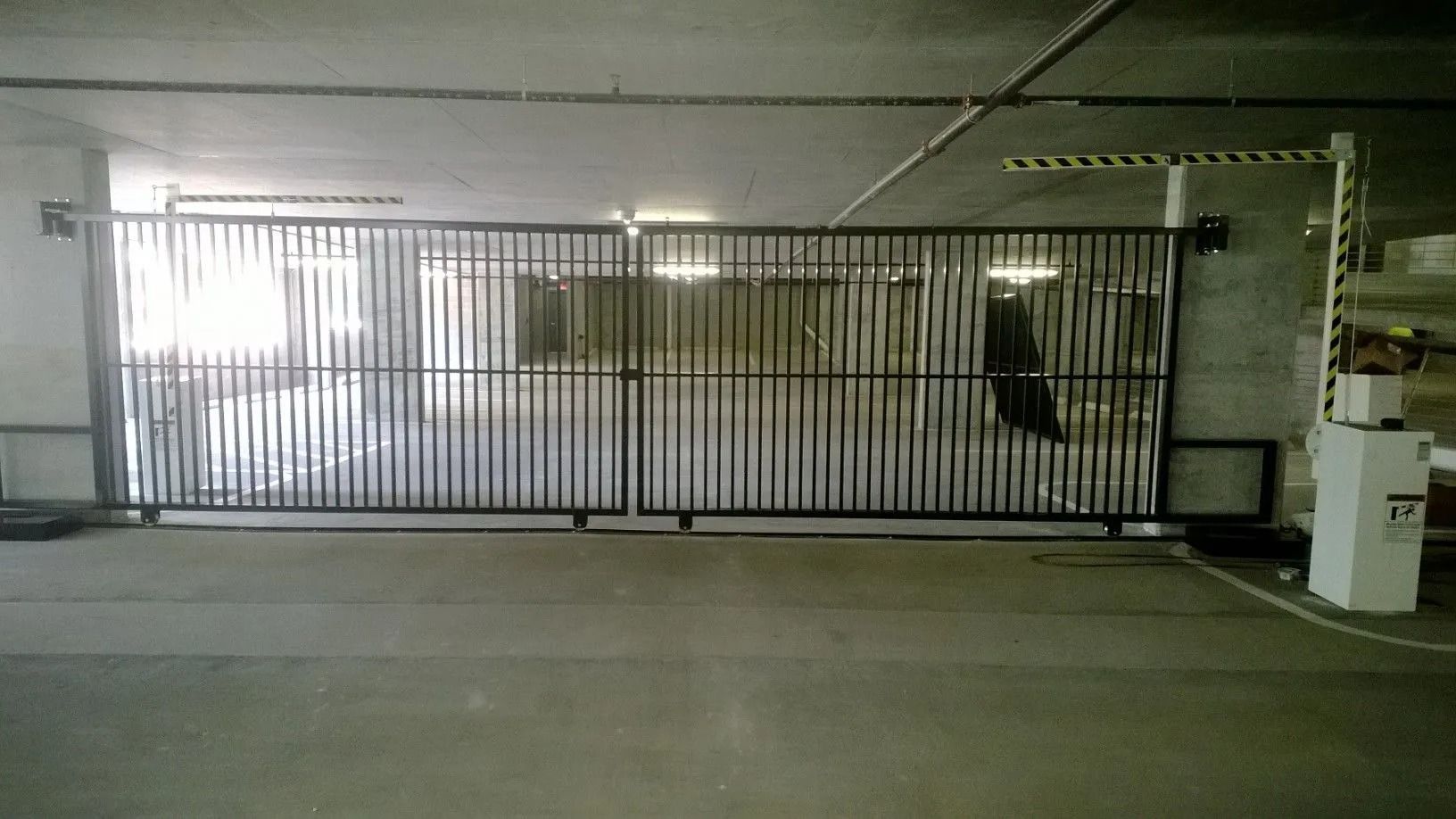 Closed metal gate across a dim parking garage entrance