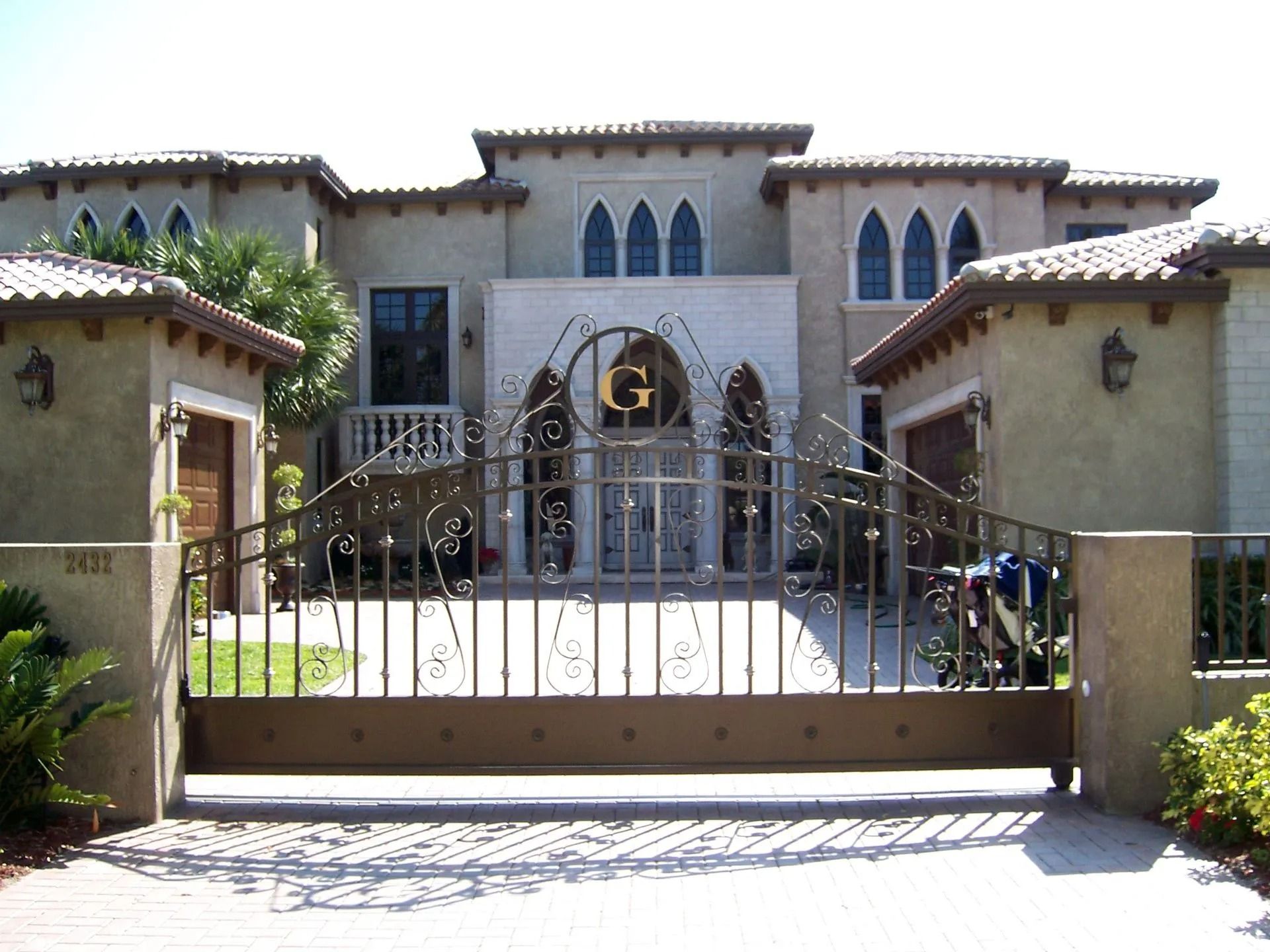 Large Mediterranean-style house behind a gated entrance and driveway.