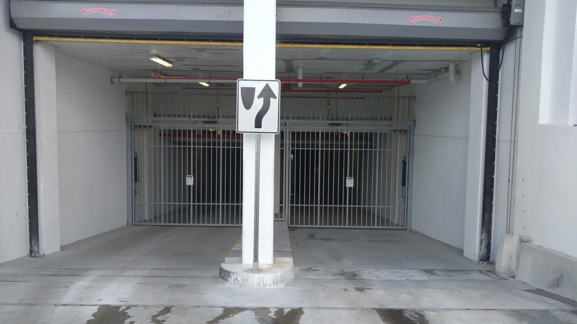 Parking garage entrance with closed metal gates and a black arrow sign on a white pillar.