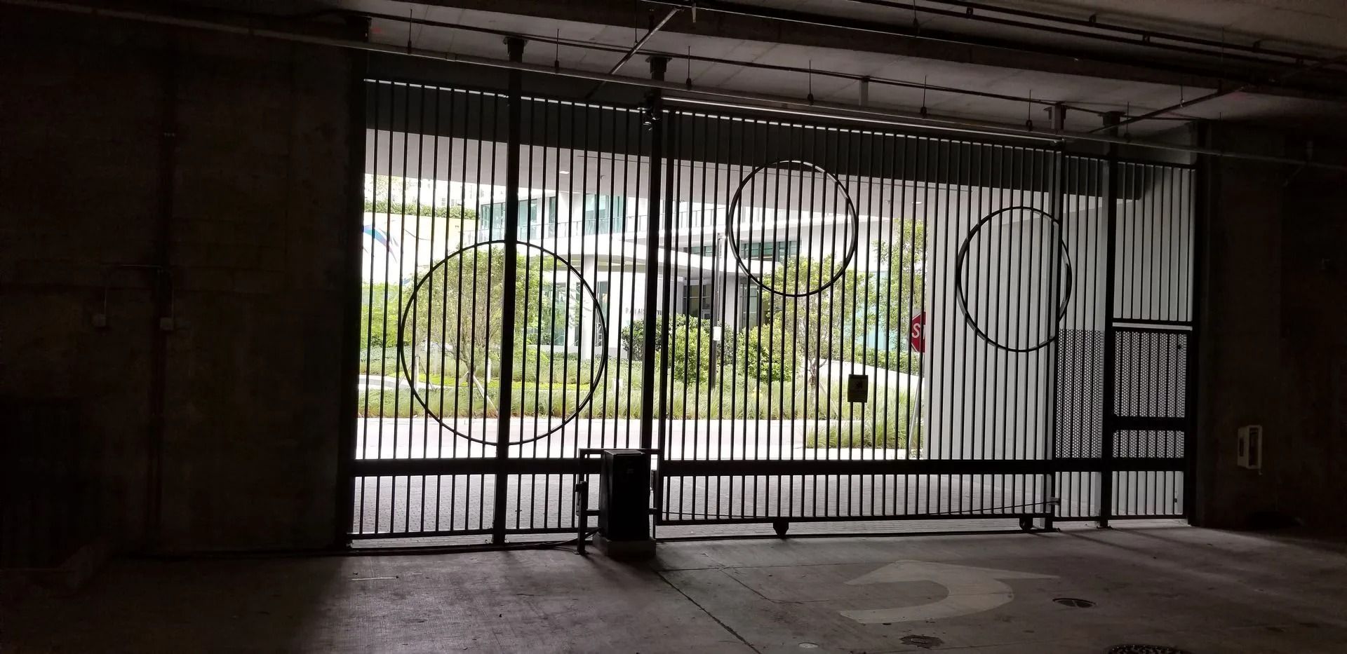 Empty indoor room with a large barred opening overlooking a green outdoor area