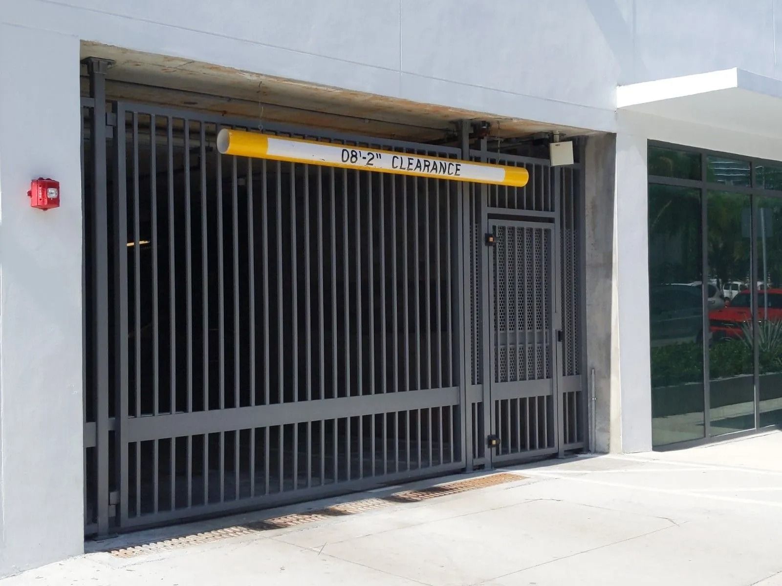Closed gray metal security gate at a building entrance with a yellow clearance bar overhead