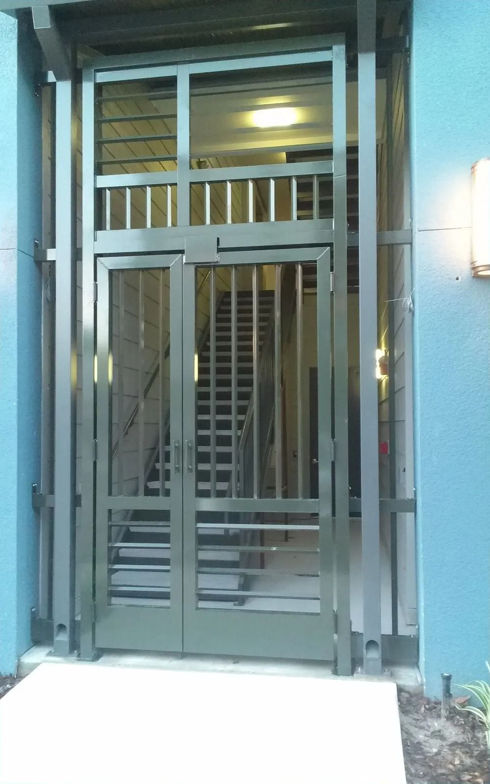 Metal security gate at a building entrance with stairs visible inside