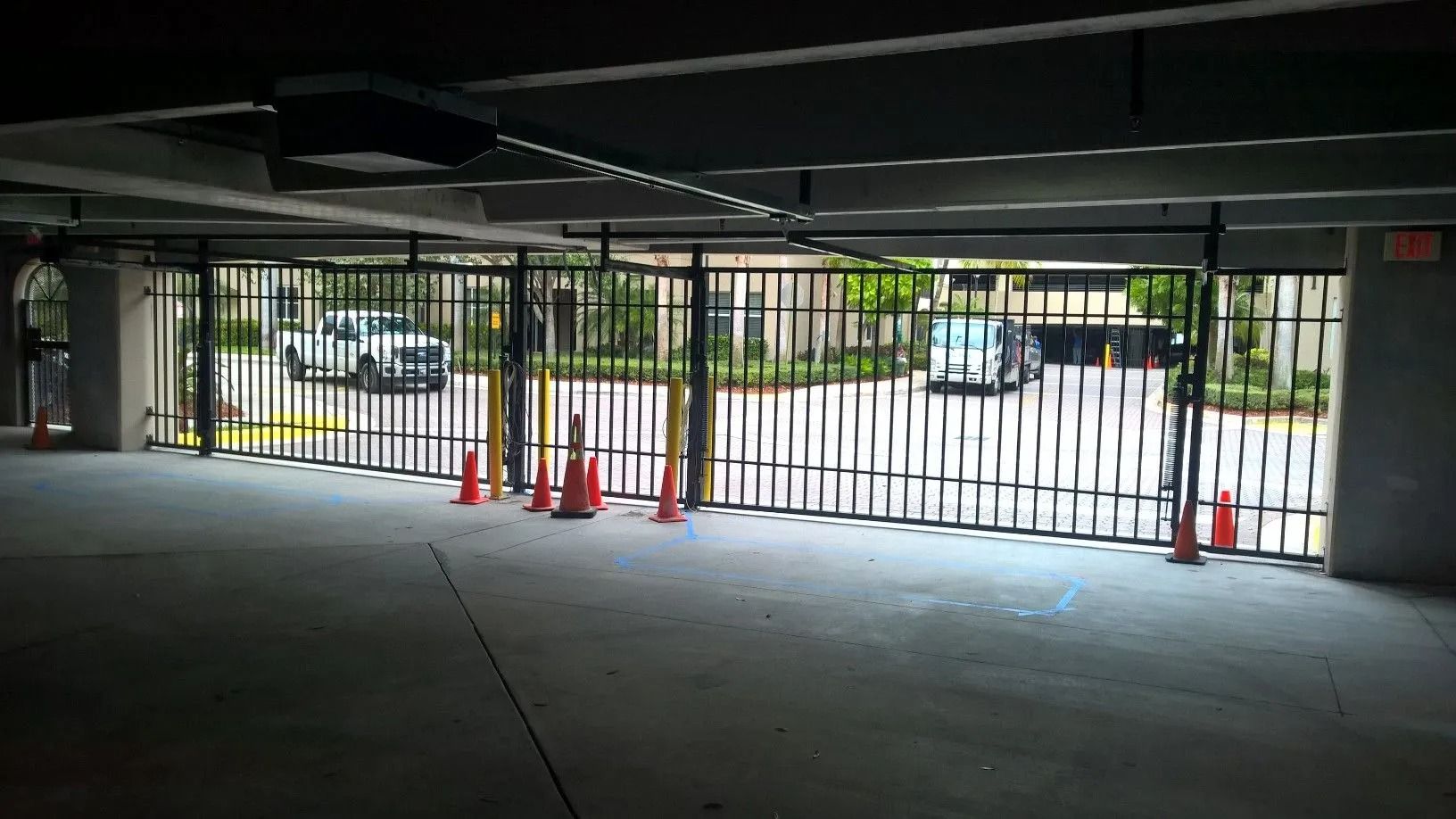 Parking garage exit with closed metal gate and orange cones blocking the driveway