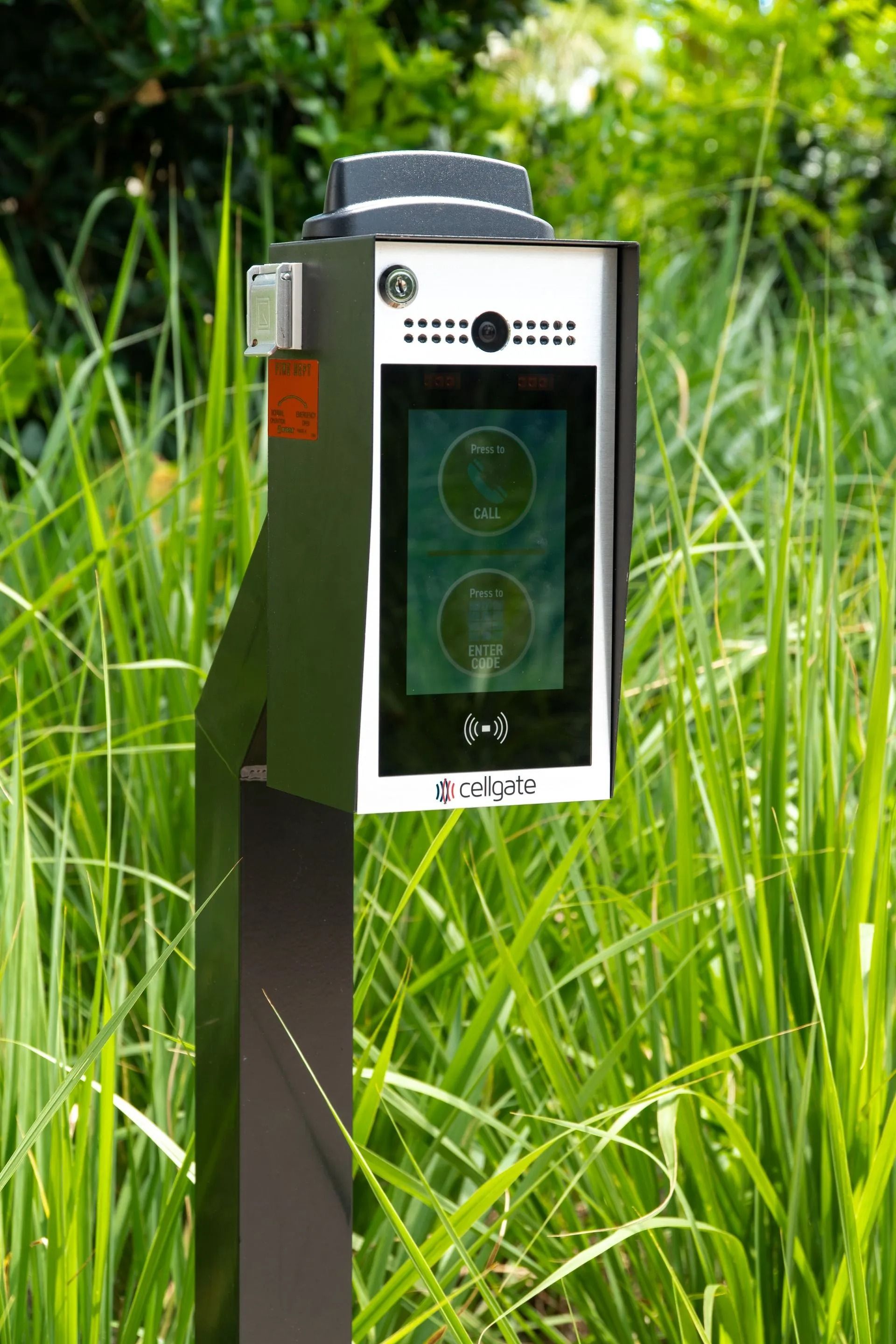 Trail camera mounted on a post in tall green grass