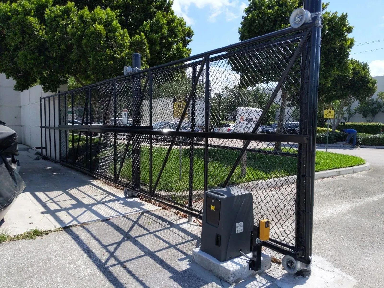 Outdoor parking payment kiosk with keypad and speaker, mounted on a black post near yellow bollards.