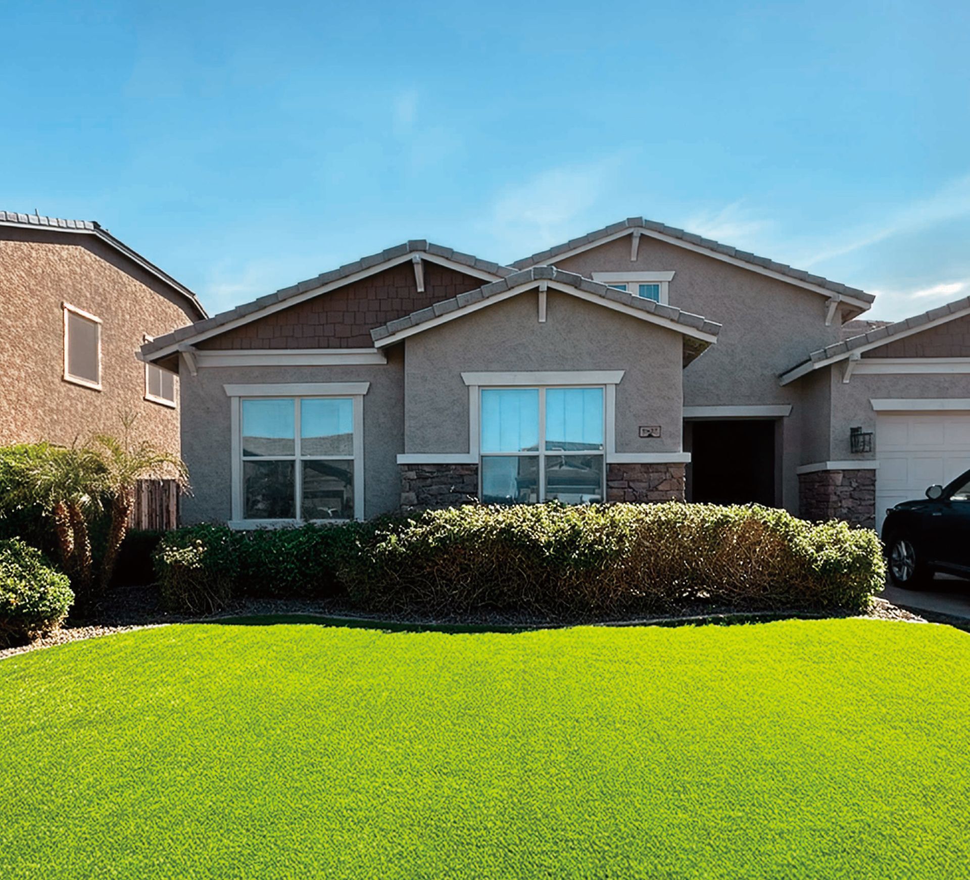 House with brown accents, green lawn, and blue sky.