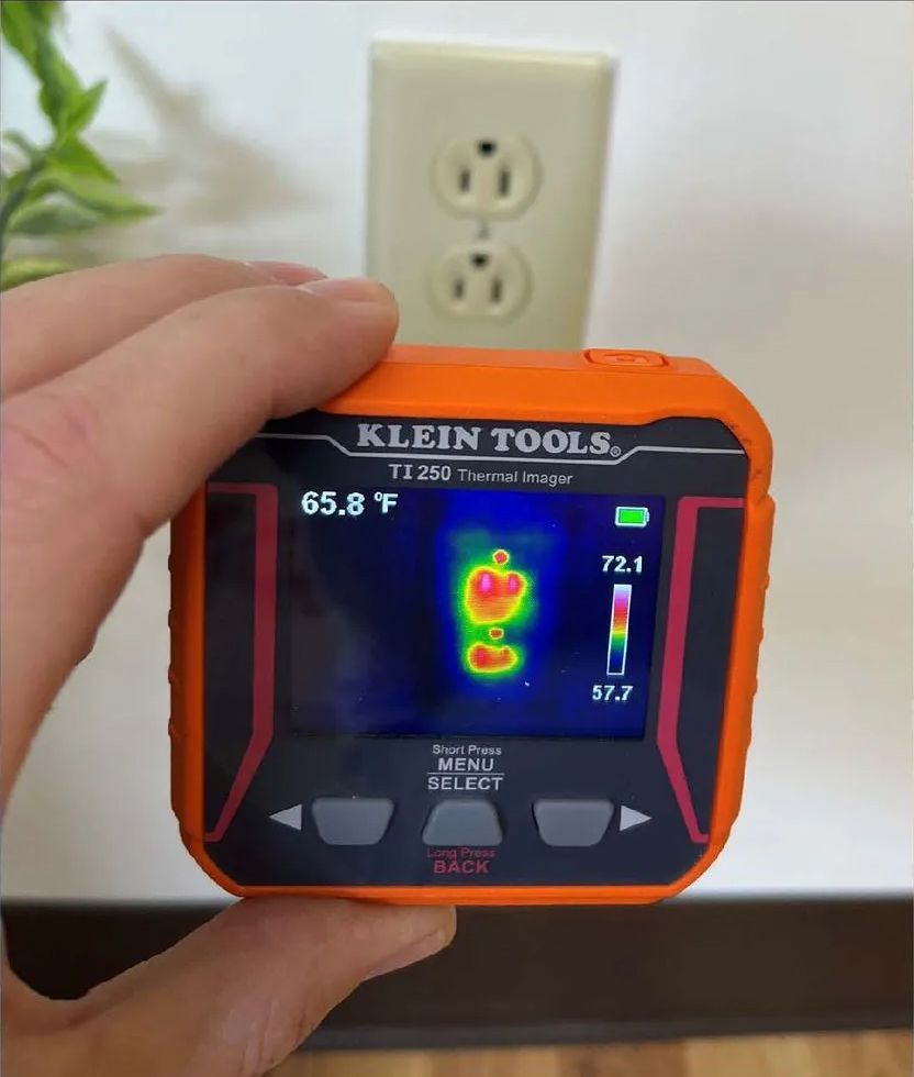 A person is holding a Klein Tools thermal imager