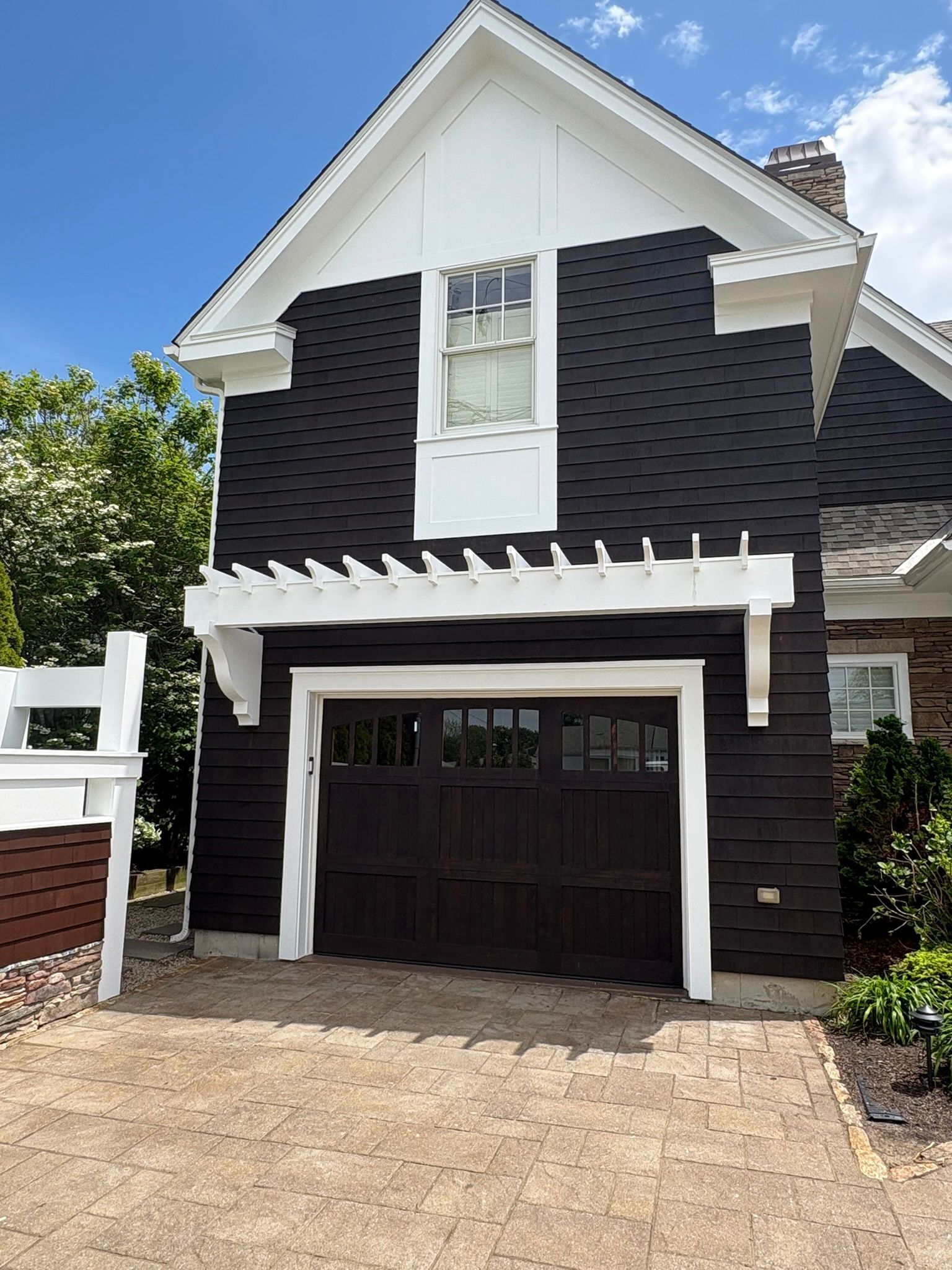 Two-story dark gray house with white trim and a garage under a peaked roof