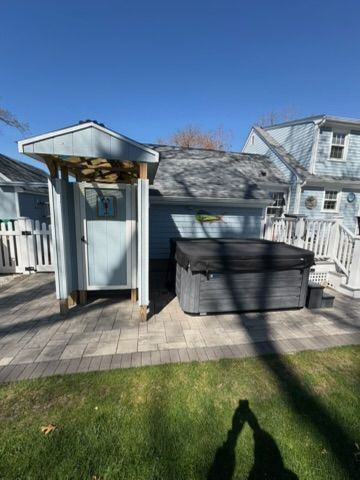 Backyard deck with a shed and black storage bin under a blue sky.