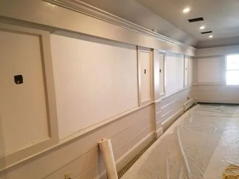White-painted interior wall with paneling and molding. Plastic sheeting covers the floor.