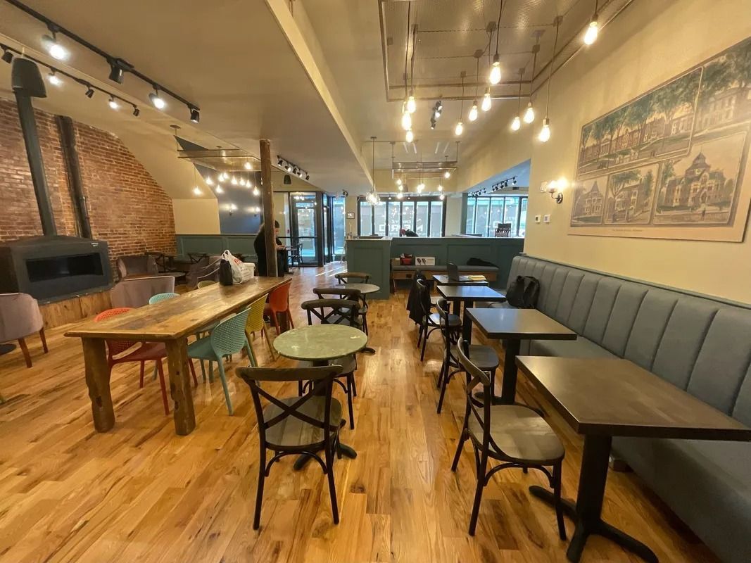 Coffee shop interior with wood floors, tables, chairs, and a fireplace.
