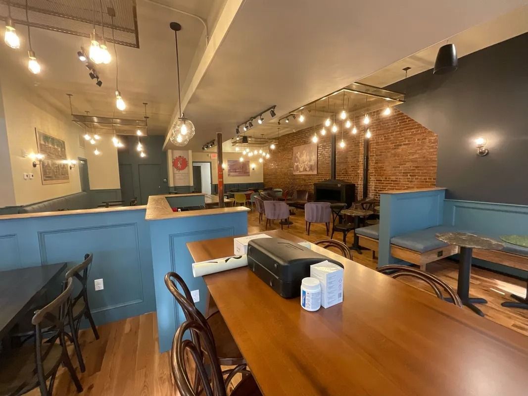 Interior of a cafe with tables, booths, exposed brick wall, and hanging lights.
