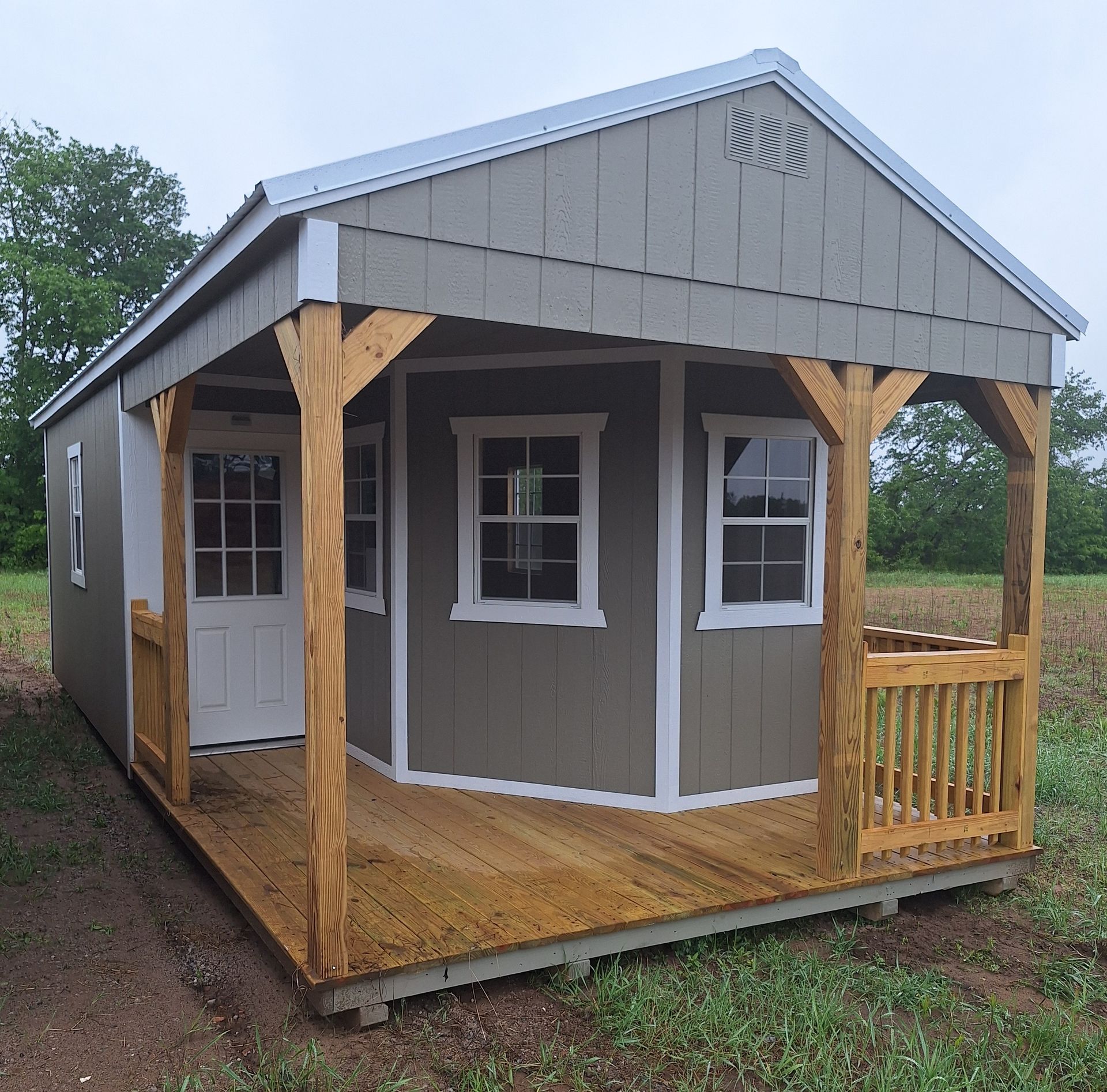 Brown-gray Deluxe playhouse with white trim and wrap around deck with a loft above the deck area