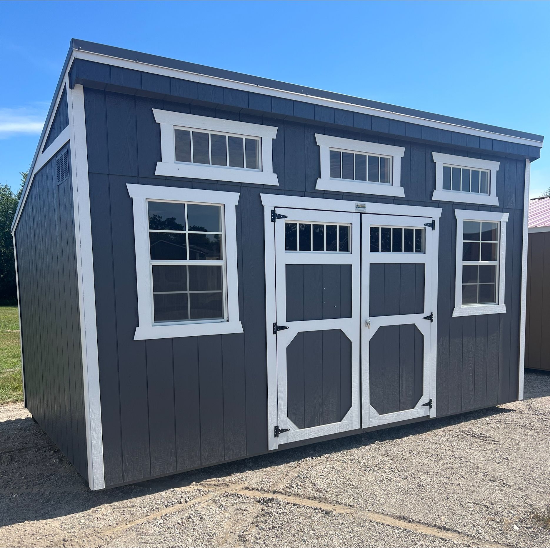 Blue side utility shed with two windows and double doors that have windows in them.
