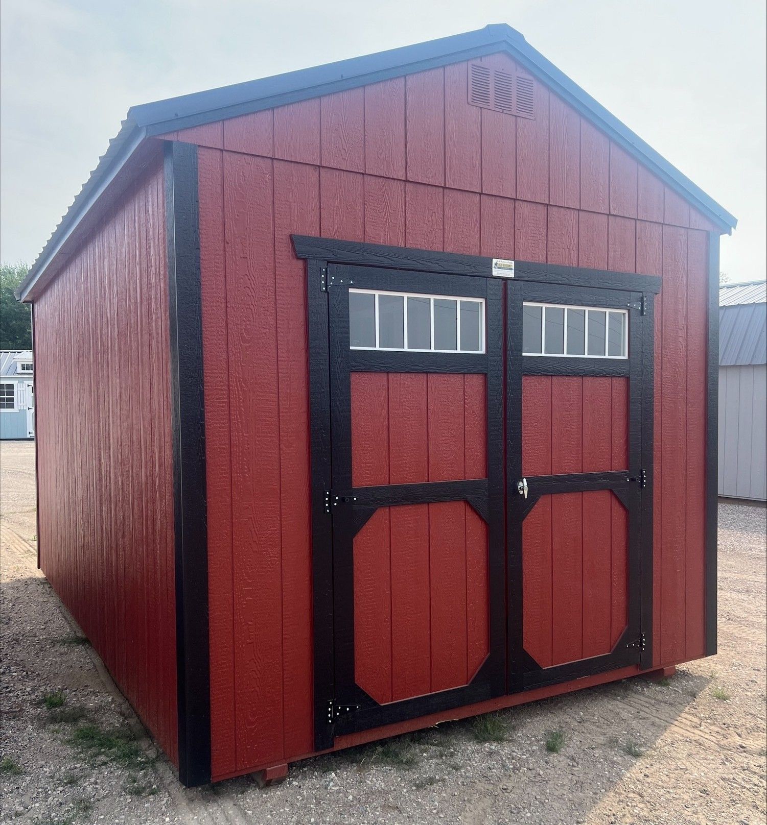 Red Utility shed with double doors that has windows in the doors.