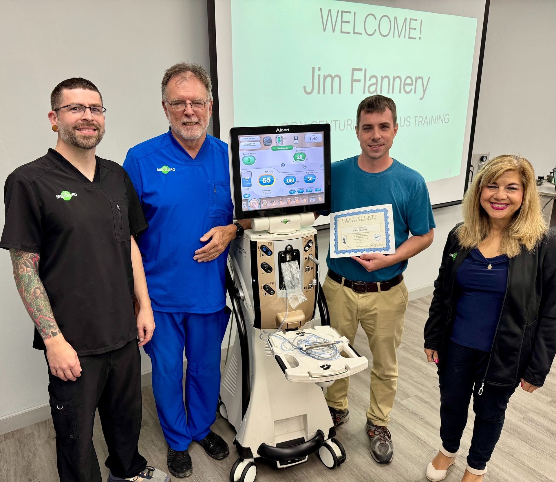 Four people pose with a medical machine, one holding a certificate. 