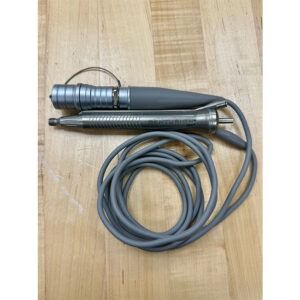 Gray medical device with a coiled cord, lying on a wooden surface.