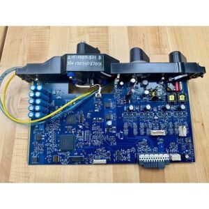 Blue circuit board with attached components; black housings, yellow and green wires, on a wooden surface.