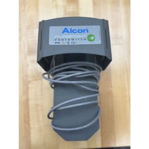 Alcon Accurus footswitch, gray with a coiled cable on a wooden surface.