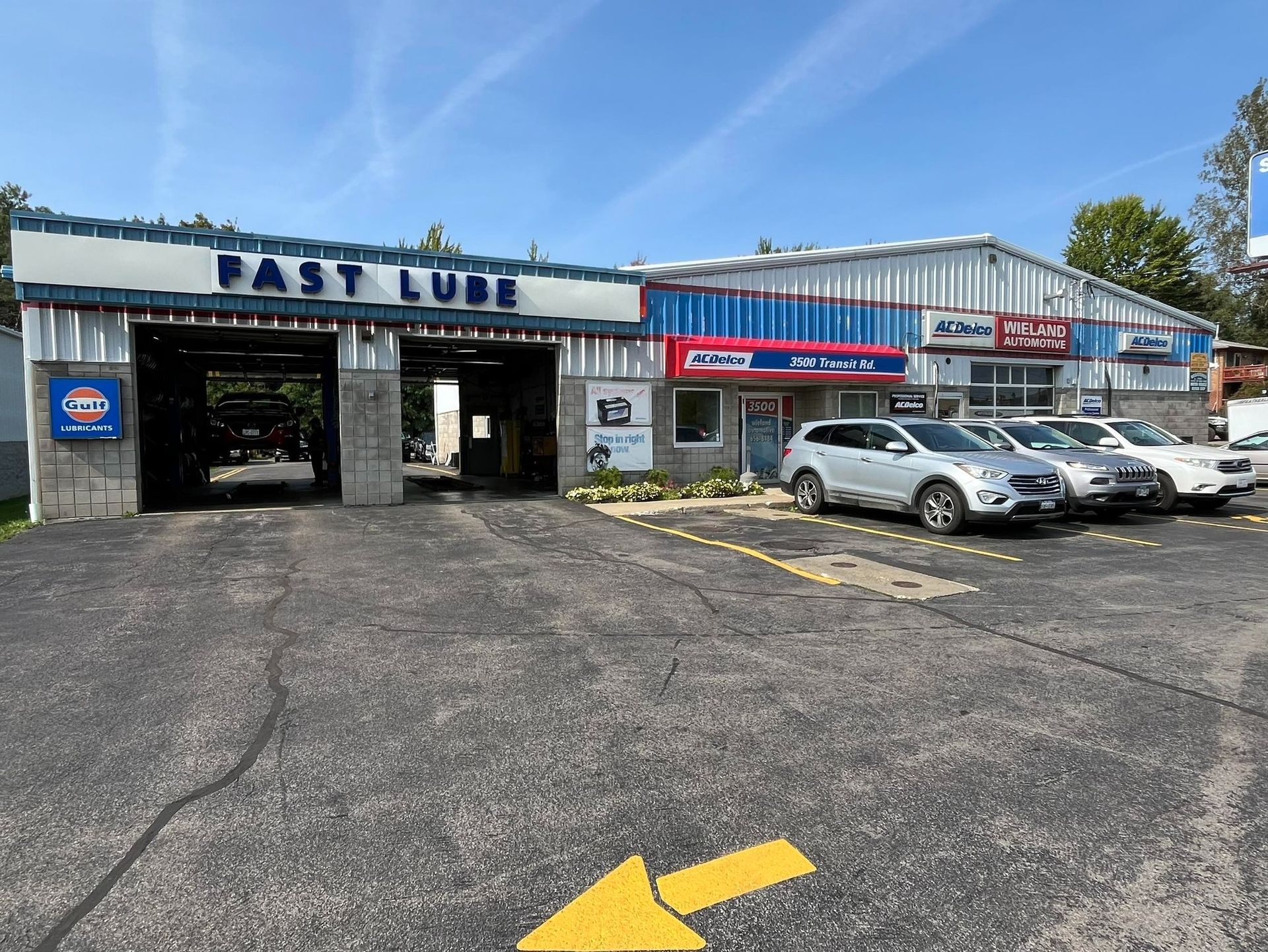 Exterior view of a Fast Lube and auto repair shop with cars parked outside, blue sky.
