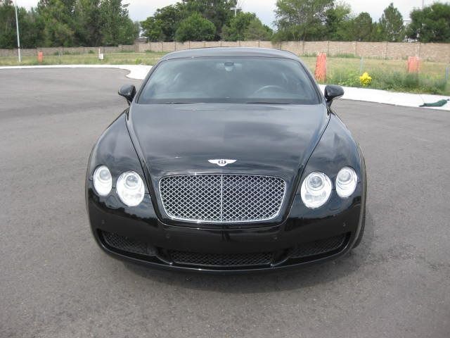 Black Bentley Continental coupe parked on asphalt.