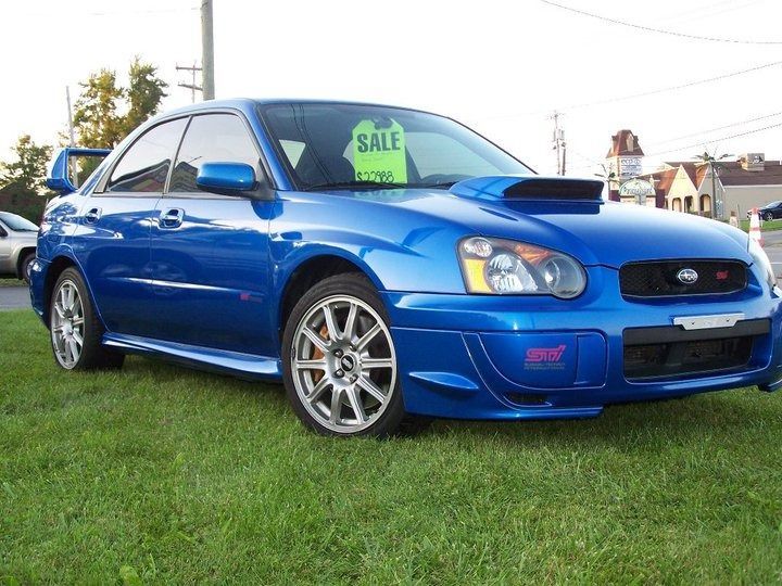 Blue Subaru Impreza WRX STI sports car parked on grass, for sale.