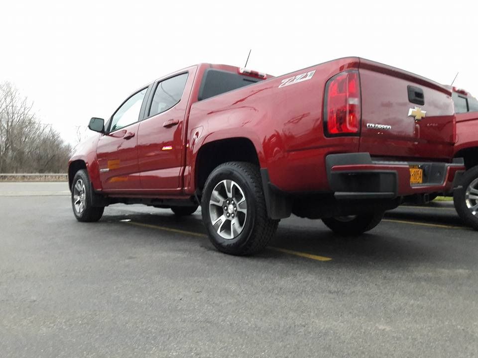 A sunny day at a Fast Lube and auto repair shop. Blue sky, gray buildings, and a silver car.