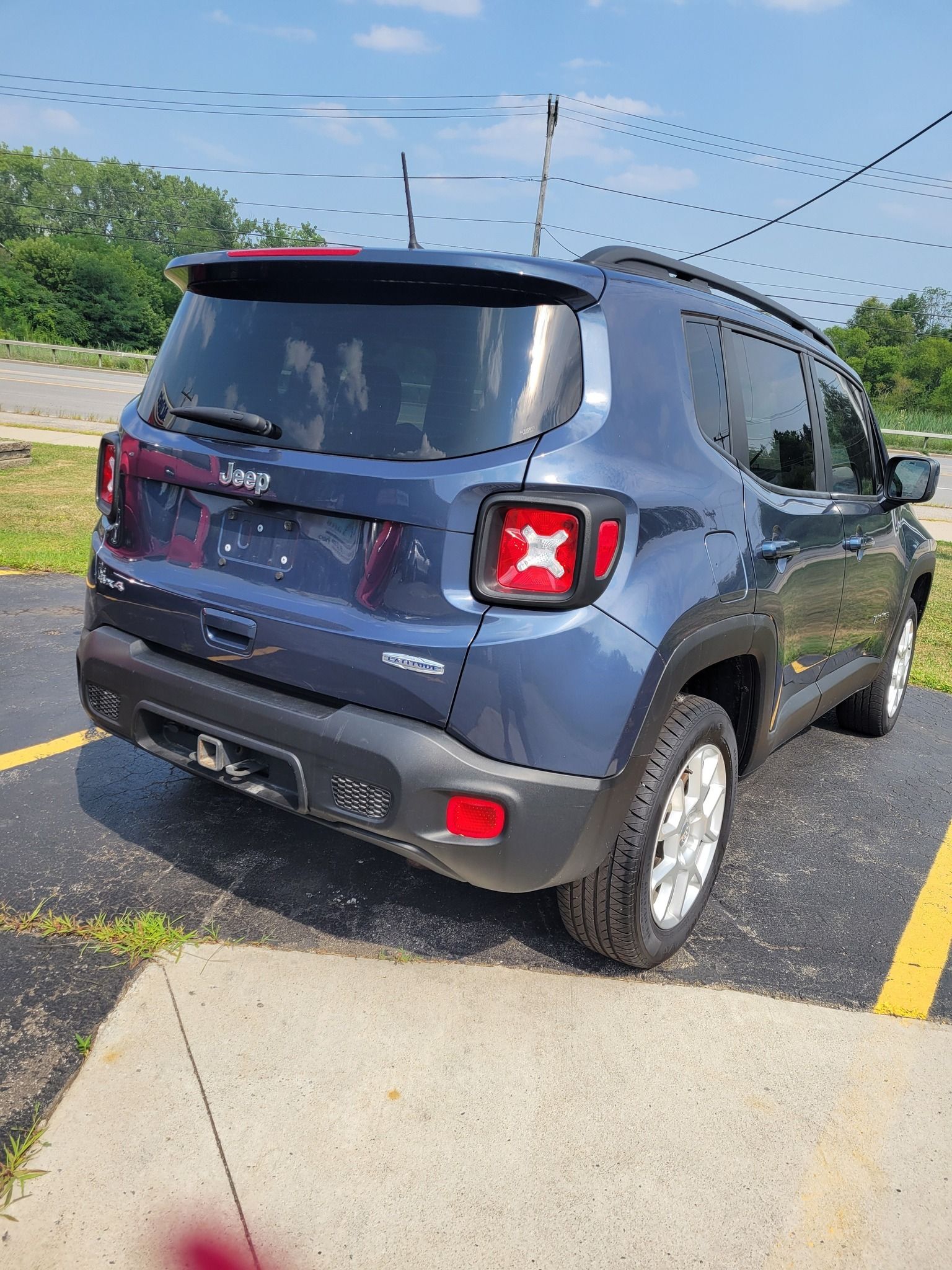 Blue Jeep Renegade parked on pavement.