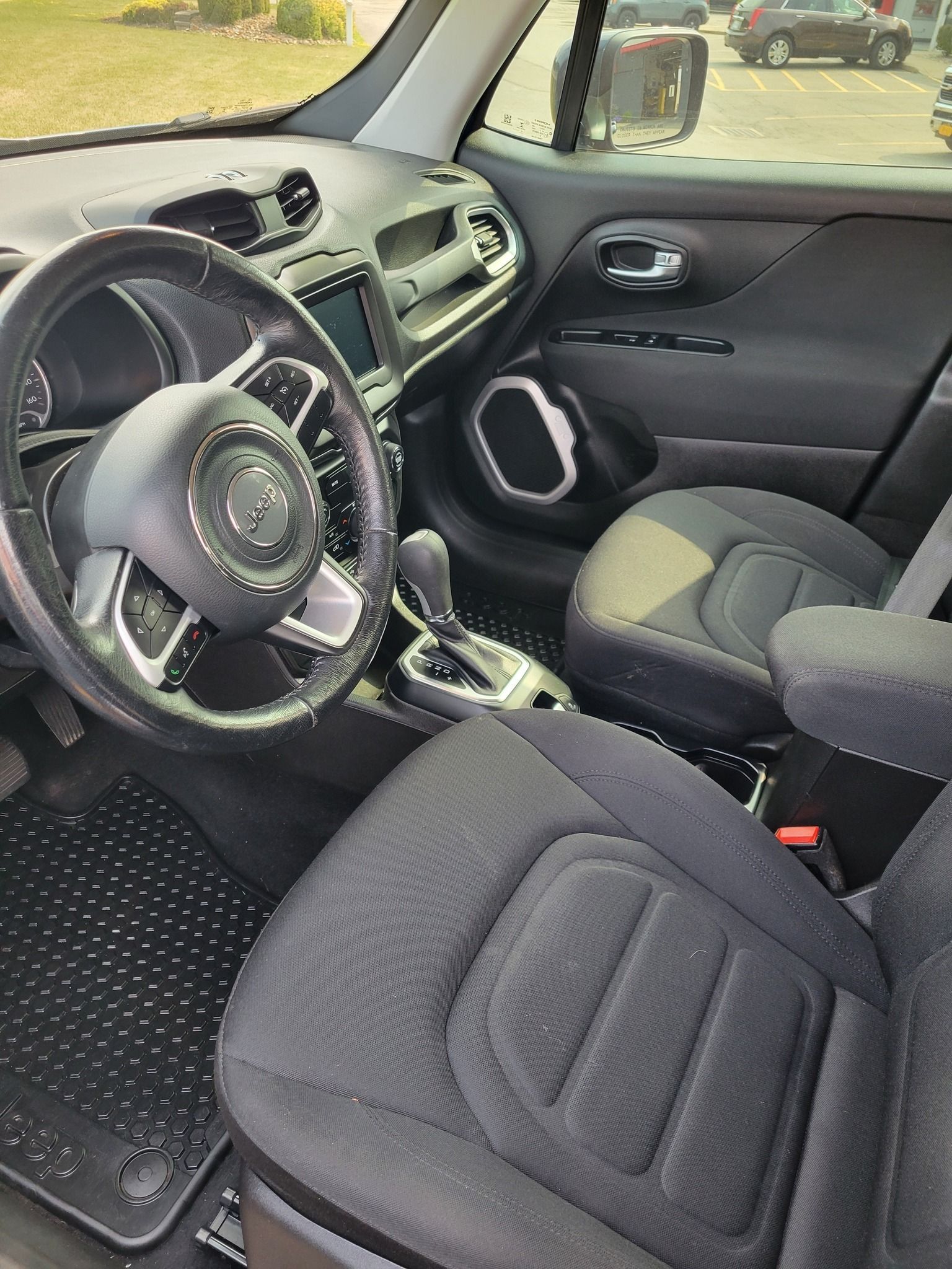 Interior of a Jeep Renegade, black seats and dashboard, steering wheel in view.