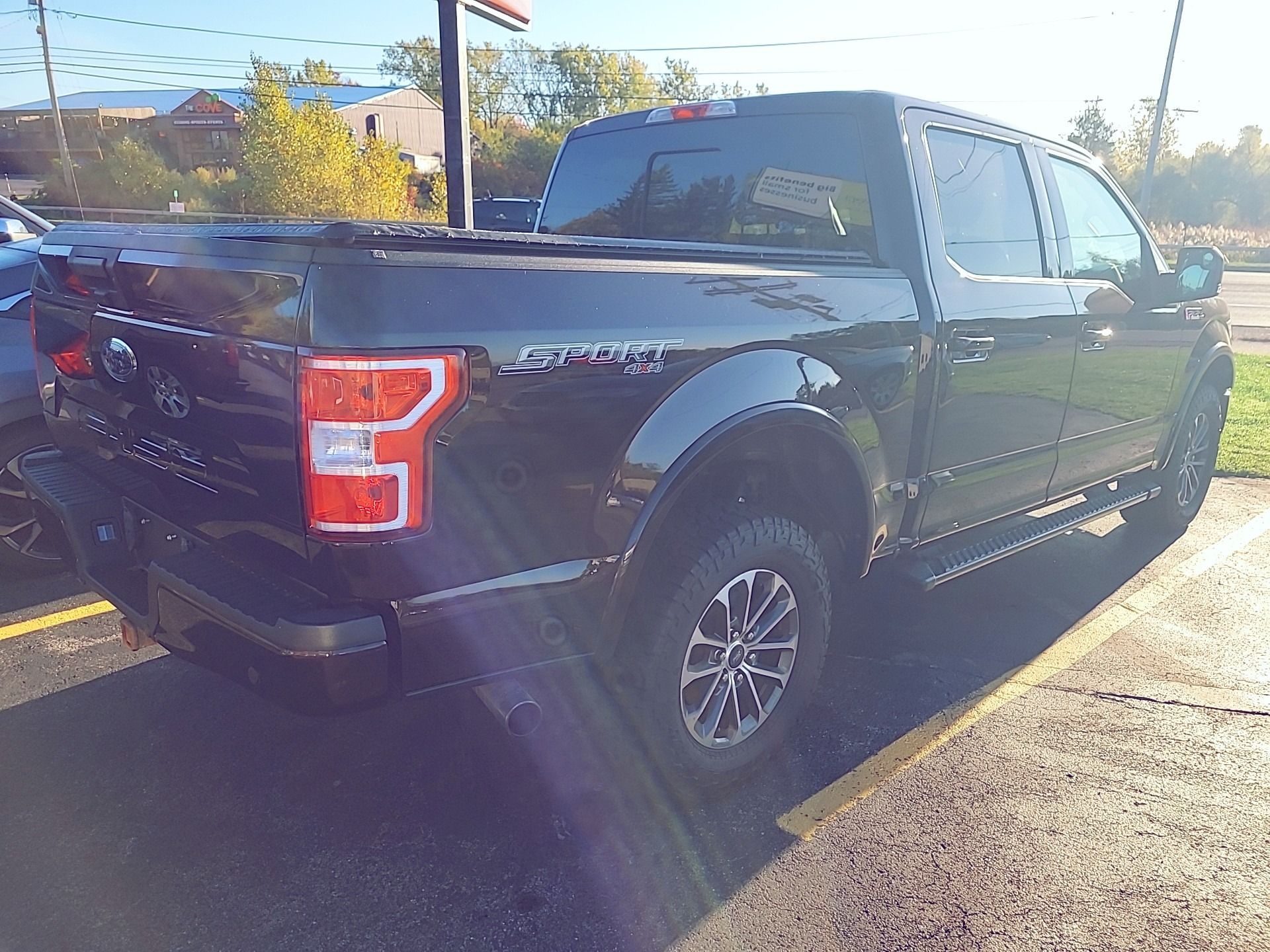 Black Ford F-150 Raptor pickup truck parked outside on a sunny day.