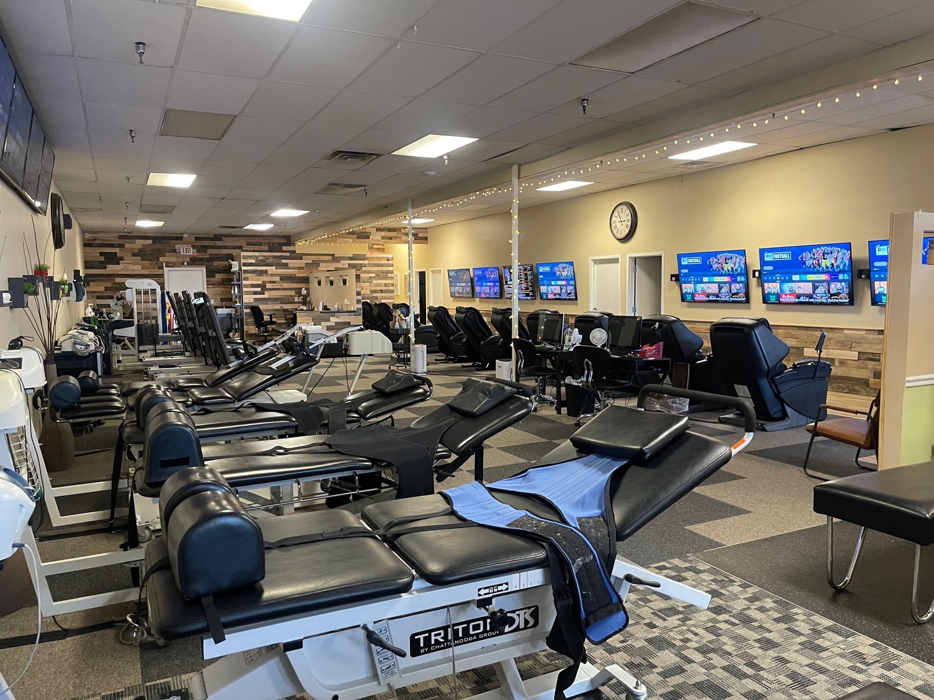 A large room filled with lots of massage tables and massage chairs.