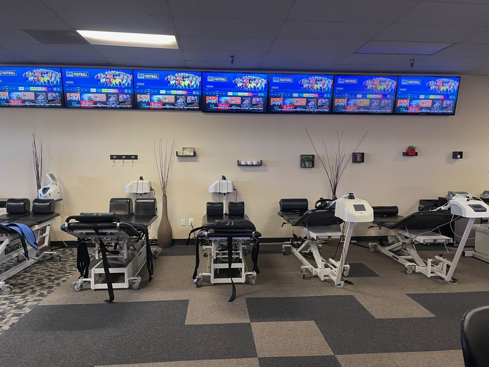 A room filled with lots of exercise equipment and monitors on the wall.