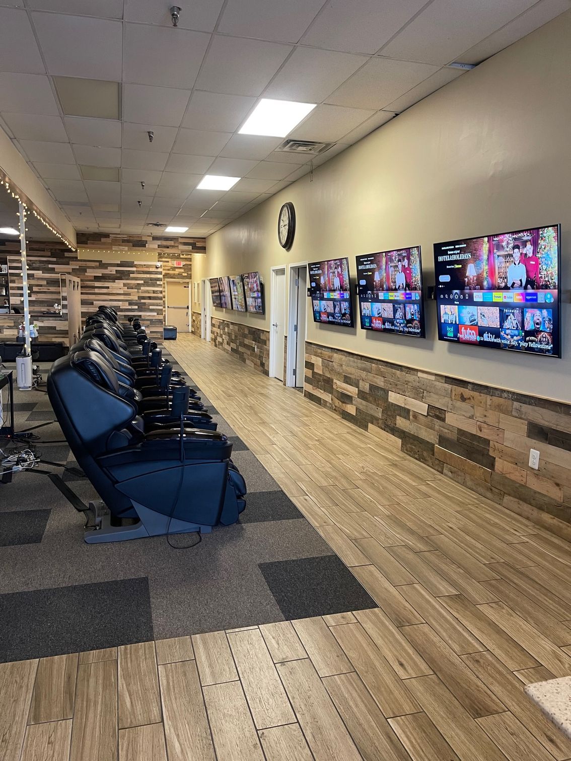 A long hallway in a physical therapy clinic with a lot of monitors on in the wall.