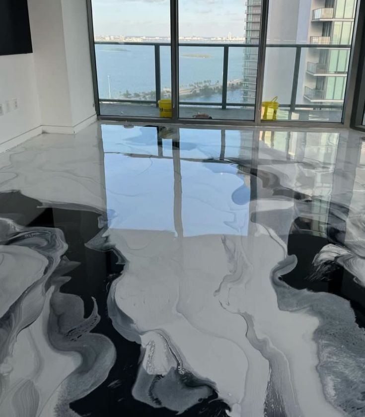 Modern apartment interior with glossy marble floor, abstract black-and-white rug, and ocean-view windows.
